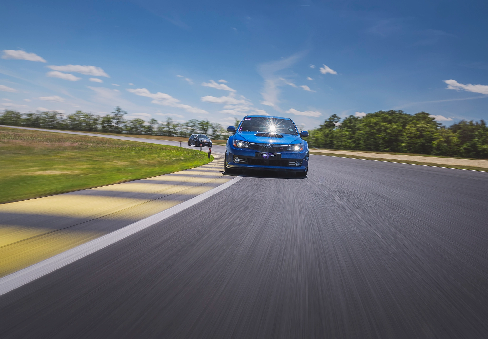 Blue Subaru WRX on track with second car behind